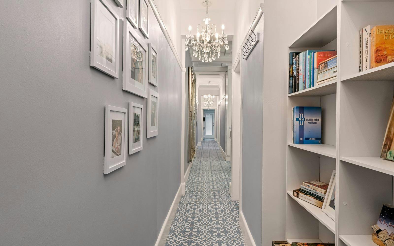 Newly renovated art deco hallway with 1930s style tiles, pendant lighting, white shelves and light grey-blue painted walls