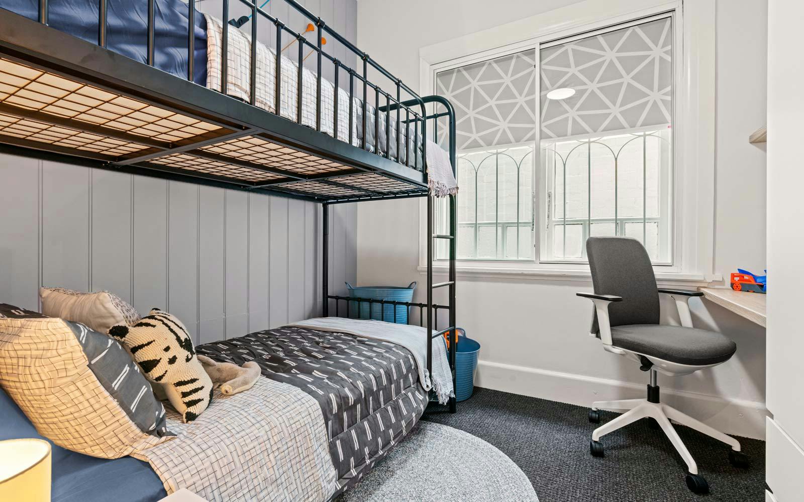 Freshly renovated children's bedroom with bunk beds and a desk and chair