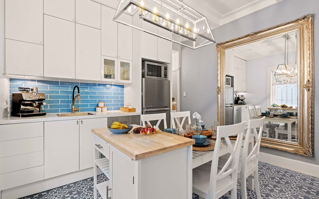 Newly renovated kitchen with blue subway tiles, white and oak timber bench, tiled floors and white dining table