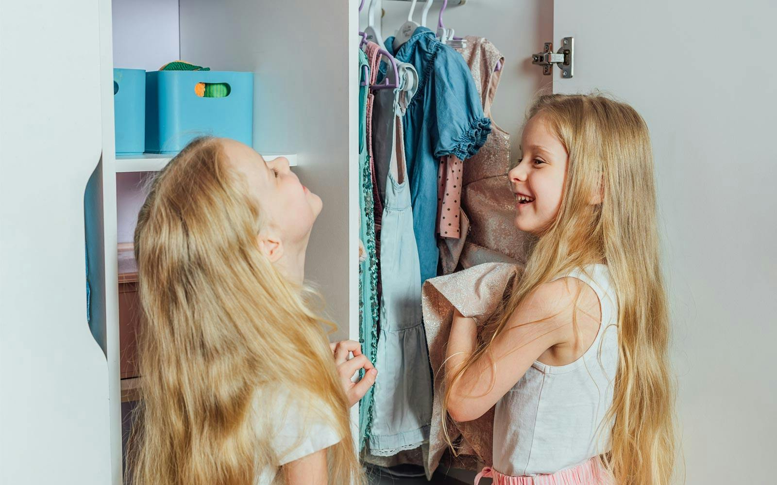Two sisters laughing and looking at clothes in the closet