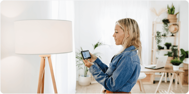 Woman checking electrical consumption of lamp at home