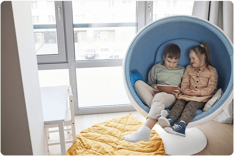 Brother and sister watching a tablet in a cosy egg chair